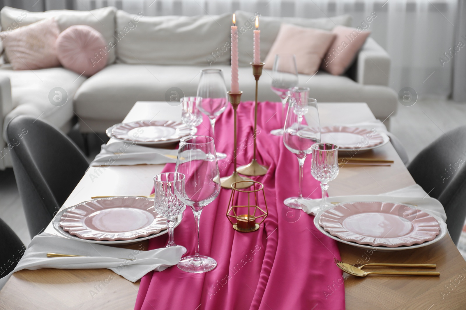 Photo of Beautiful table setting with burning candles and pink accent in dining room