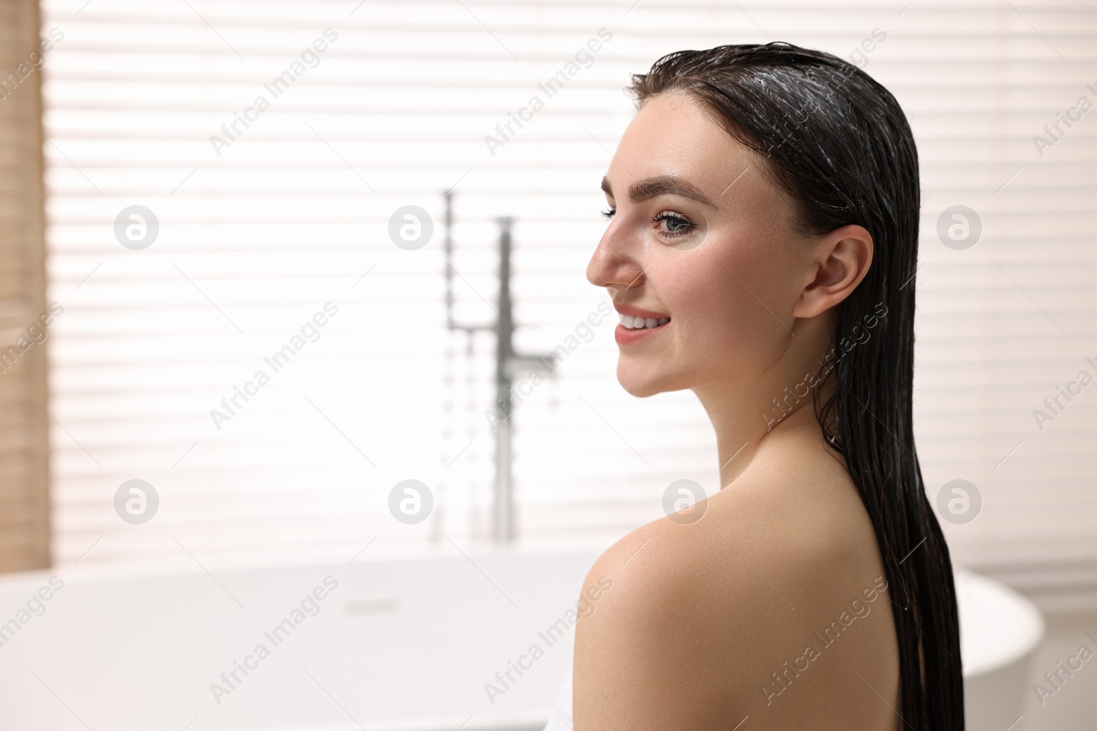 Photo of Smiling woman with applied hair mask in bathroom. Space for text