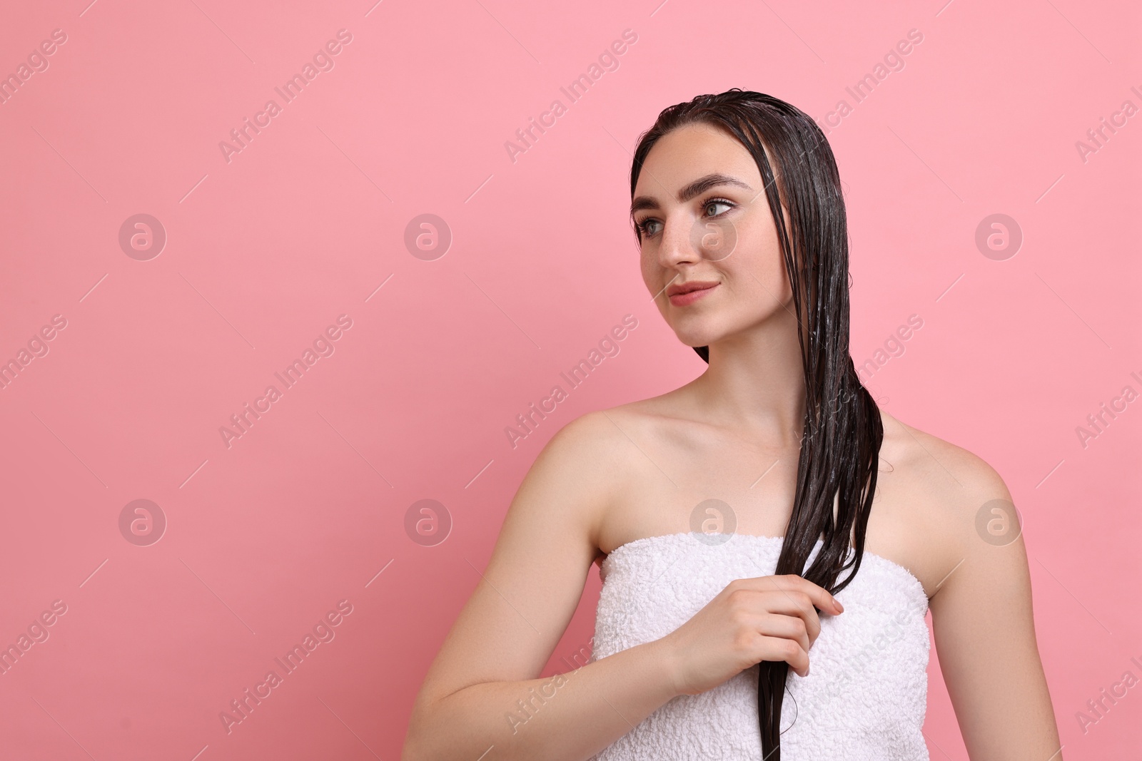 Photo of Beautiful woman applying hair mask on pink background. Space for text