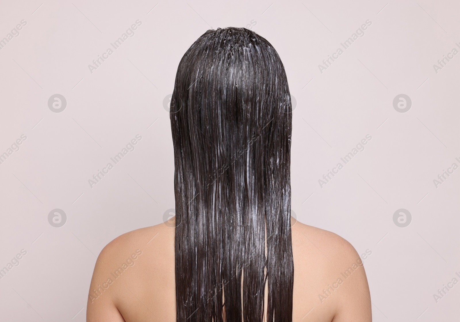 Photo of Woman with applied hair mask on light background, back view