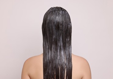 Photo of Woman with applied hair mask on light background, back view