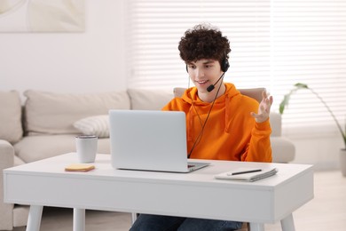 Teenager in headset having video chat via laptop at home. Remote work