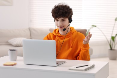 Teenager in headset having video chat via laptop at home. Remote work