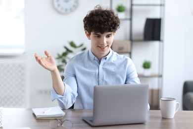 Photo of Teenager having video chat via laptop at table indoors. Remote work