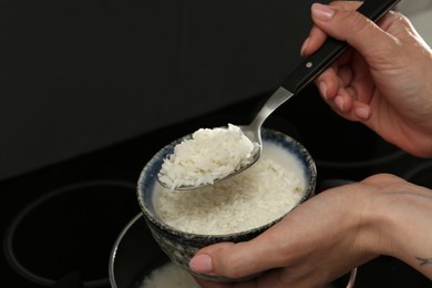 Photo of Woman taking boiled rice into bowl, closeup