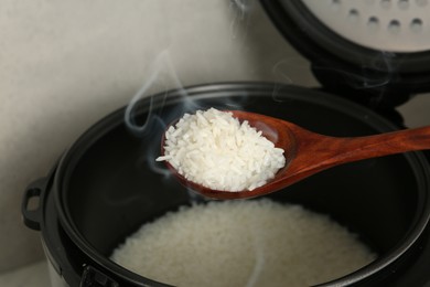 Photo of Taking boiled rice with wooden spoon on grey background, closeup