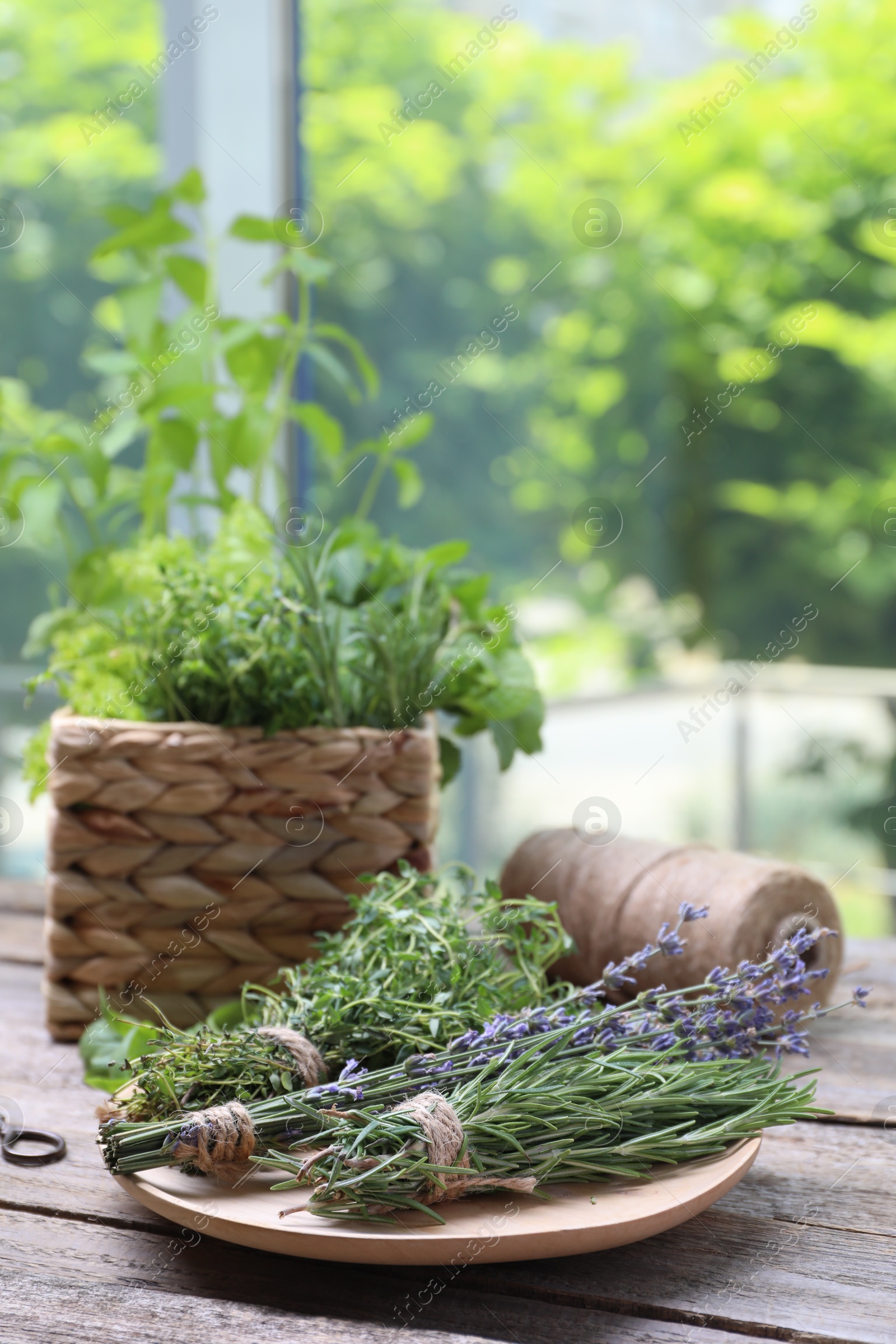 Photo of Different aromatic herbs on wooden table against blurred background