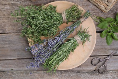 Different aromatic herbs and scissors on wooden table, flat lay