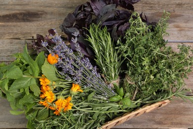 Photo of Different aromatic herbs in basket on wooden table, top view