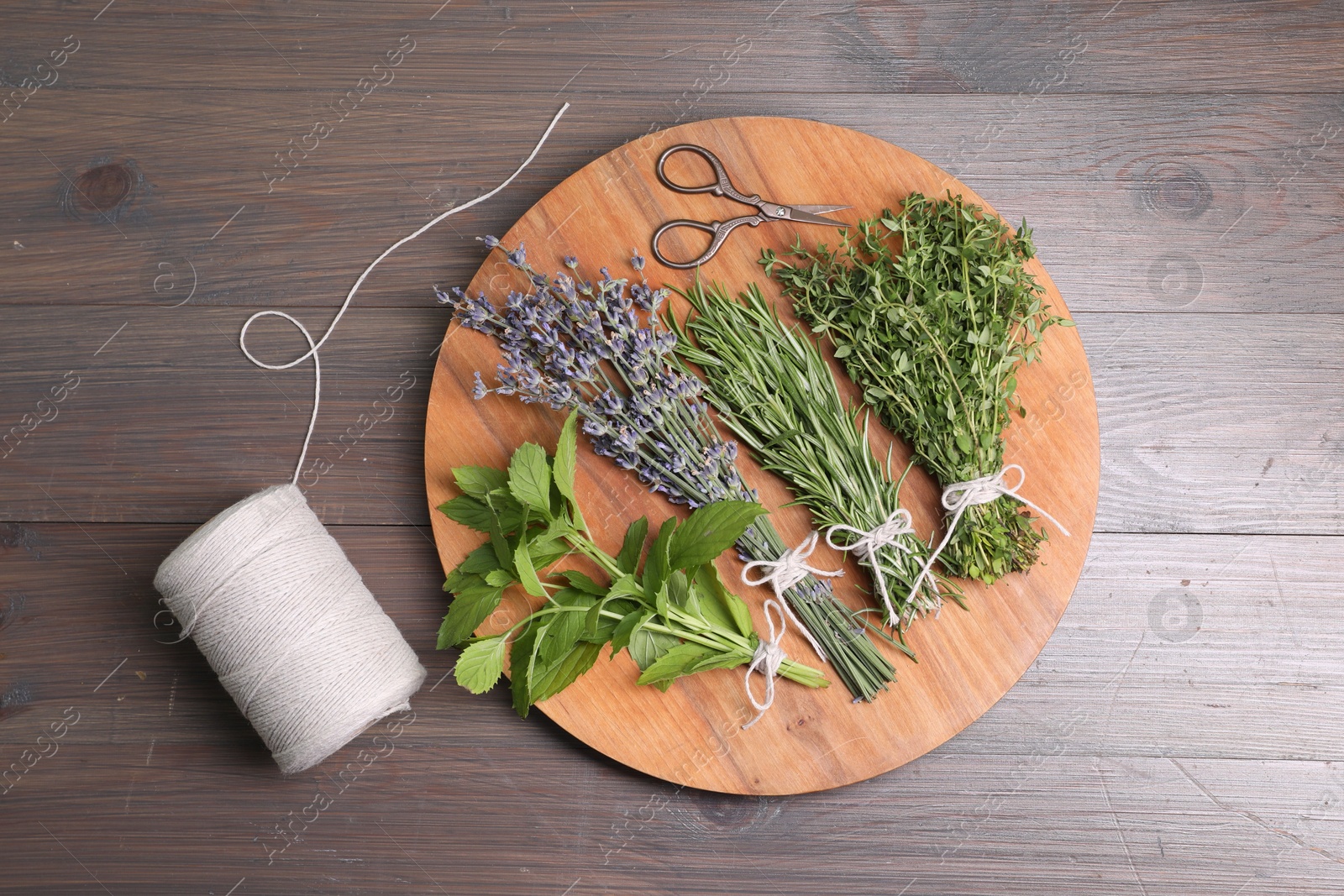 Photo of Different aromatic herbs, thread and scissors on wooden table, top view