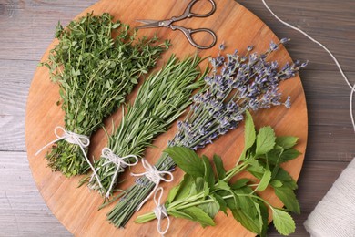 Photo of Different aromatic herbs and scissors on wooden table, top view