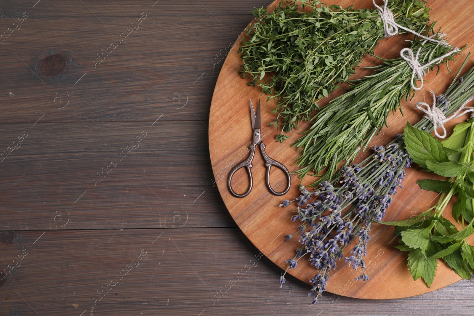 Photo of Different aromatic herbs and scissors on wooden table, top view. Space for text