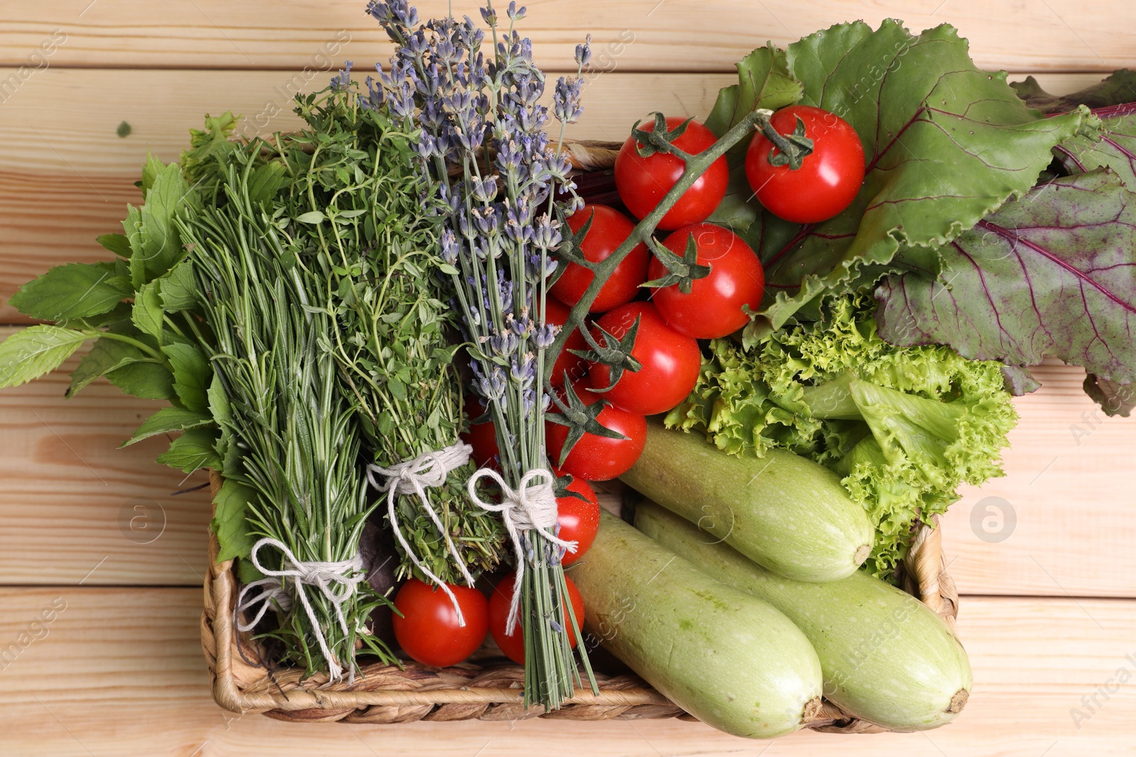 Photo of Different aromatic herbs and vegetables on wooden table, top view