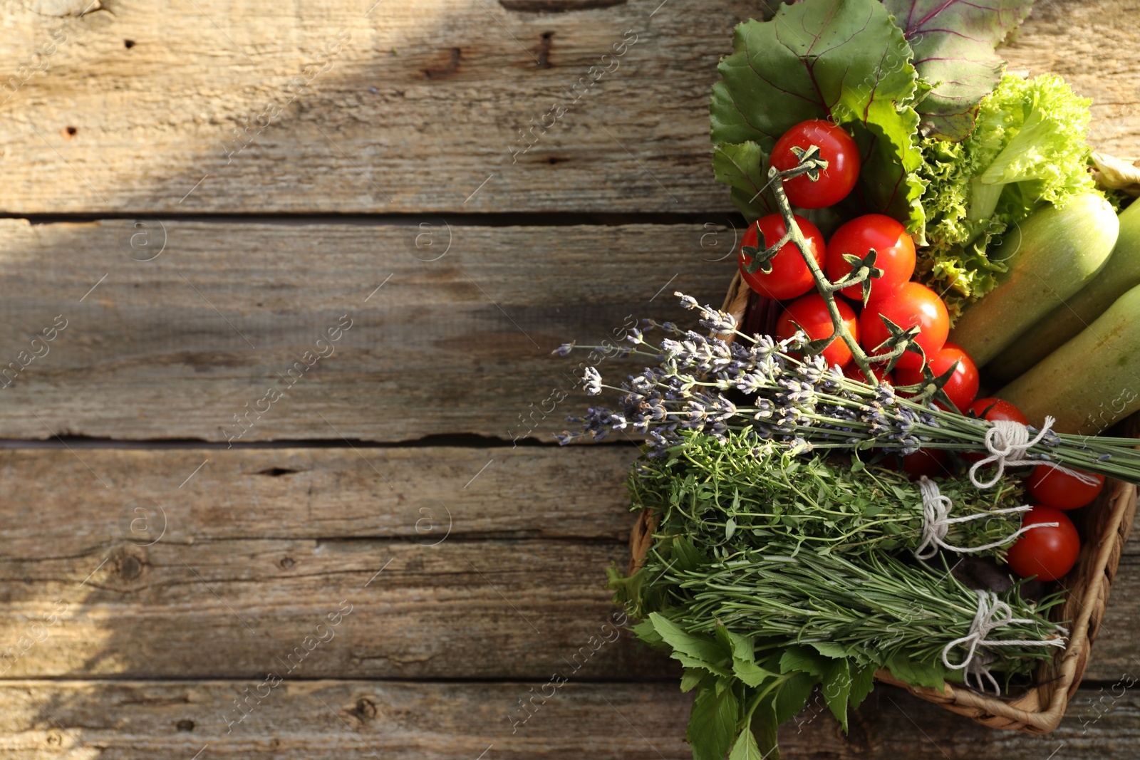 Photo of Different aromatic herbs and vegetables on wooden table, top view. Space for text