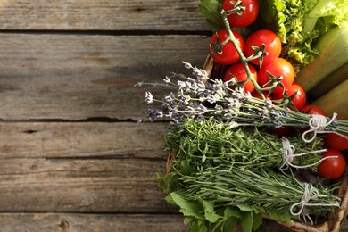 Different aromatic herbs and vegetables on wooden table, top view. Space for text