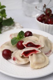 Traditional Ukrainian dumplings (varenyky) with cherries served on light table, closeup