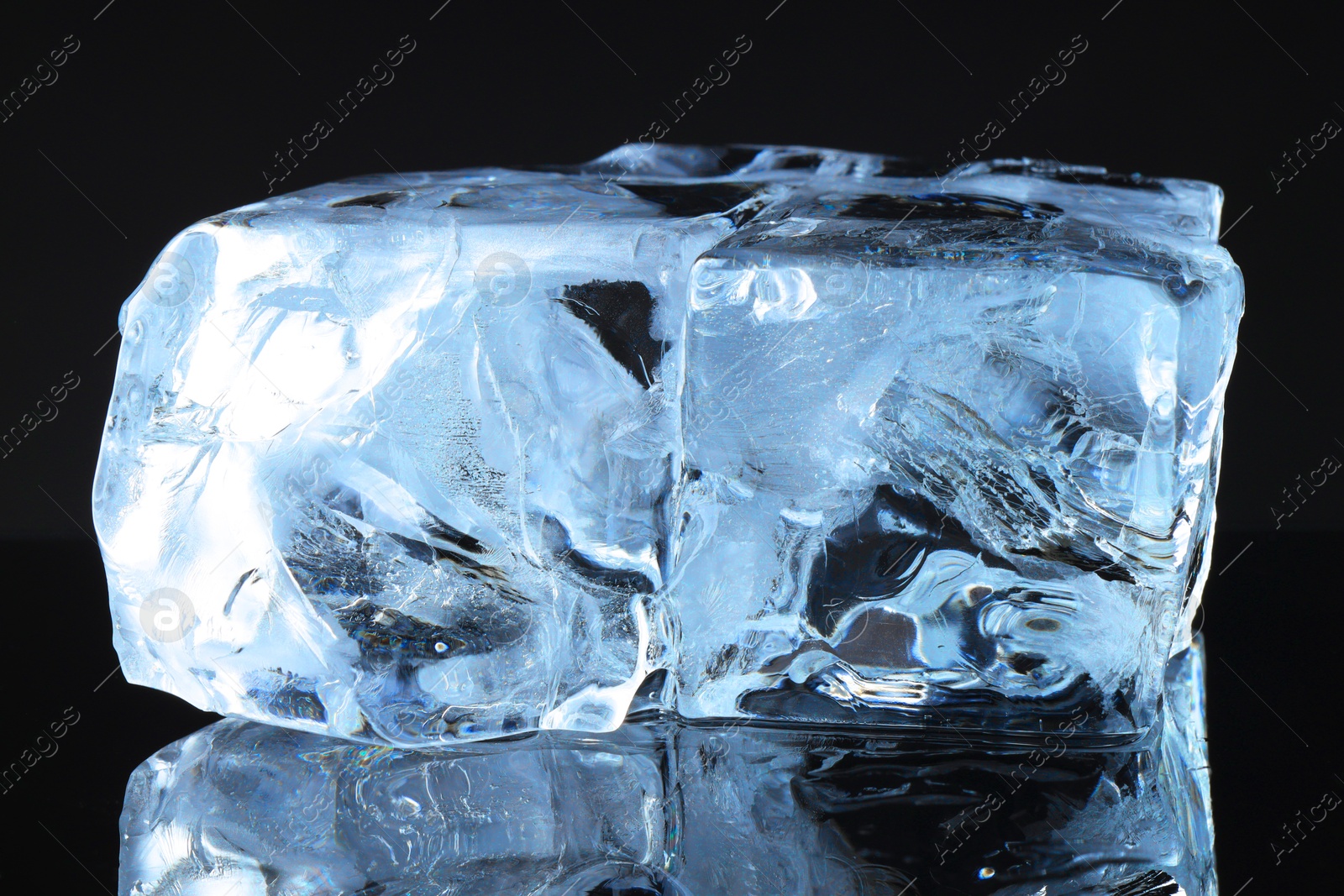 Photo of Pieces of clear ice on black mirror surface, closeup