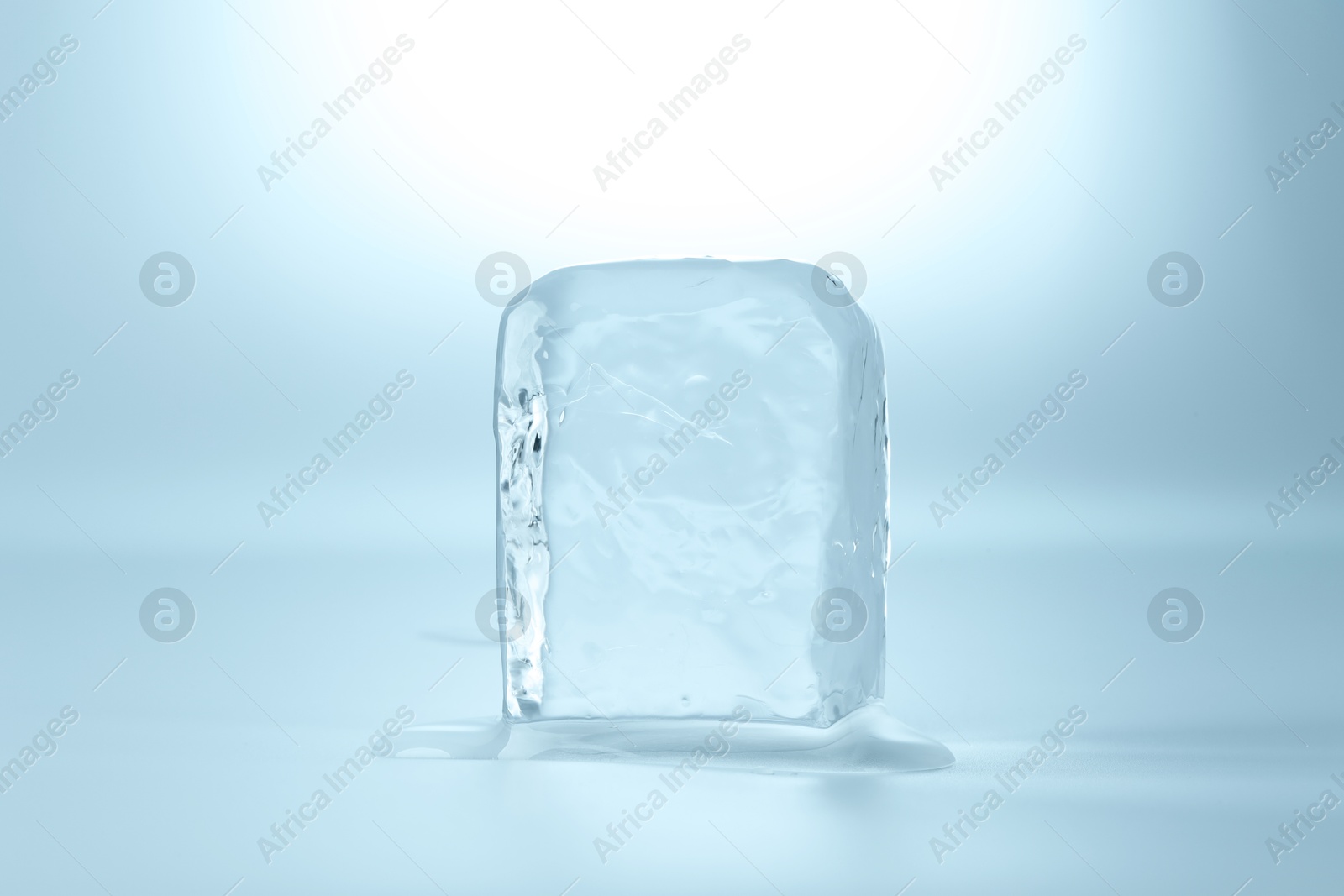 Photo of Cube of clear ice on light blue background