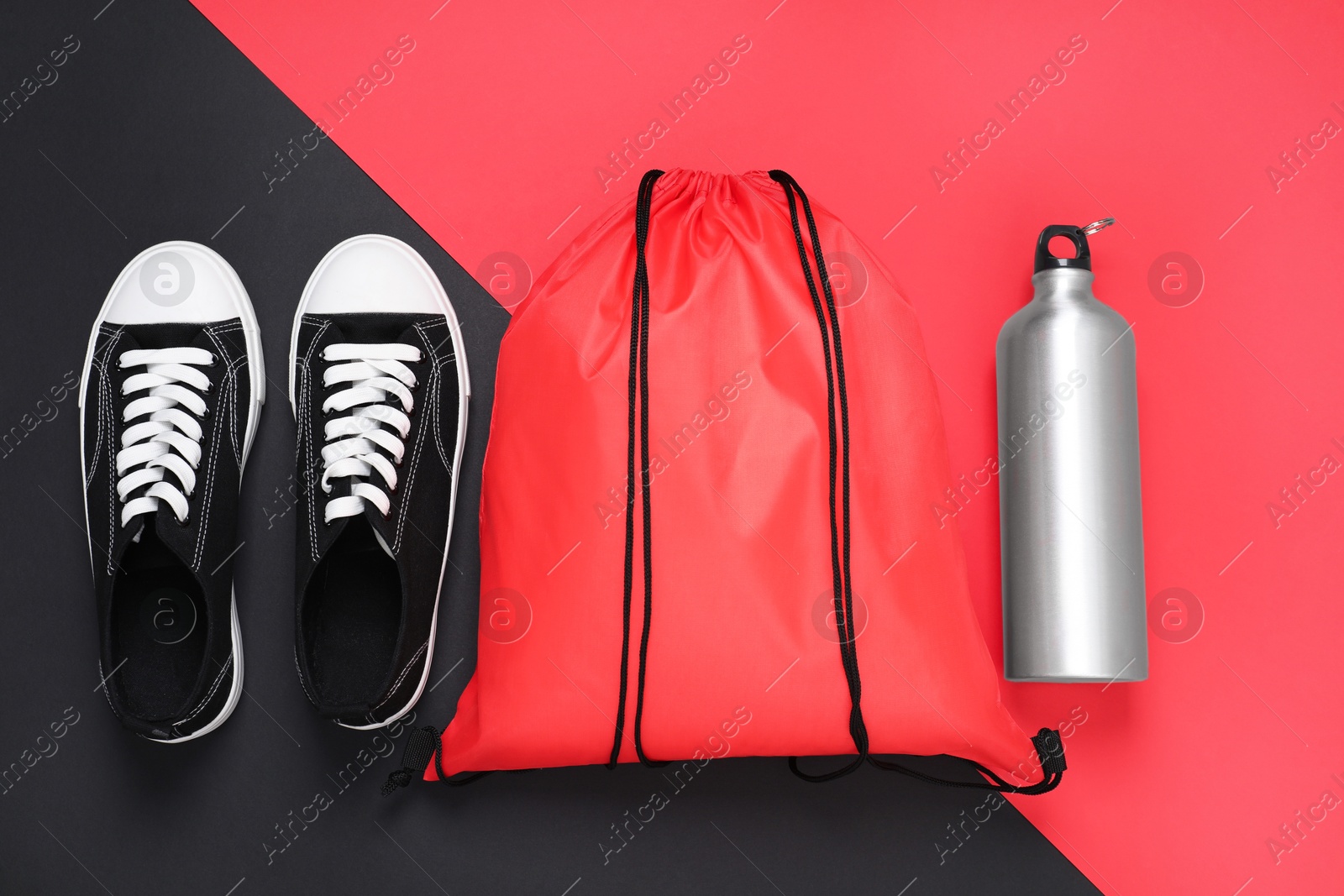 Photo of Red drawstring bag, thermo bottle and sneakers on color background, flat lay