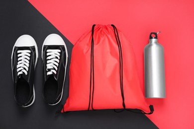 Red drawstring bag, thermo bottle and sneakers on color background, flat lay