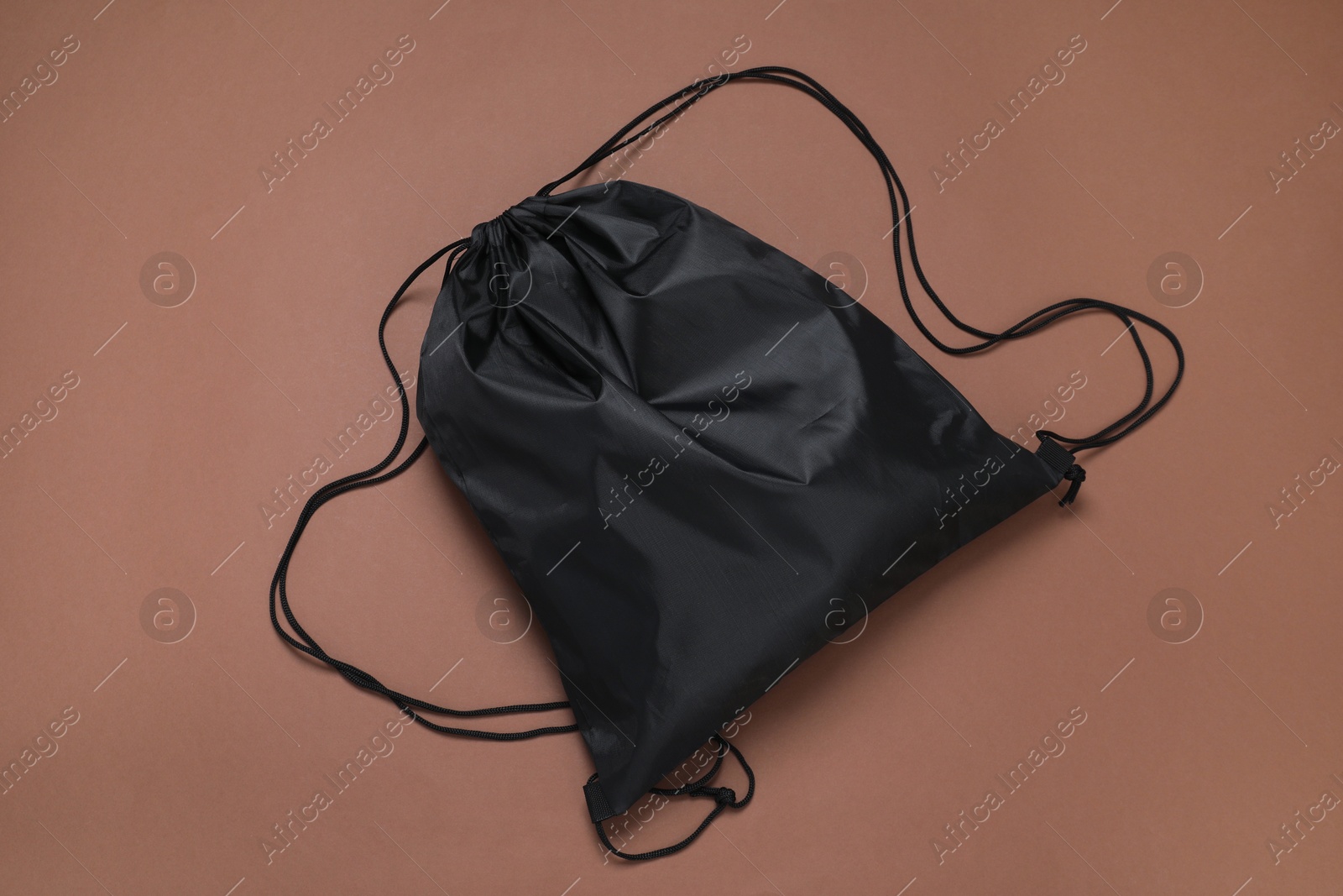 Photo of Black drawstring bag on brown background, top view