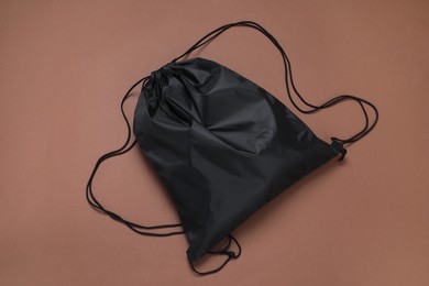 Black drawstring bag on brown background, top view