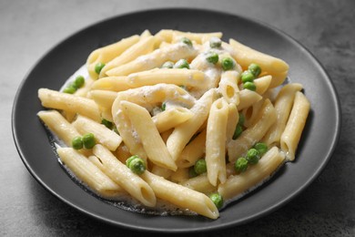 Photo of Delicious pasta with green peas and creamy sauce on grey table, closeup