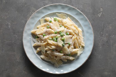 Photo of Delicious pasta with green peas, cheese and creamy sauce on grey table, top view