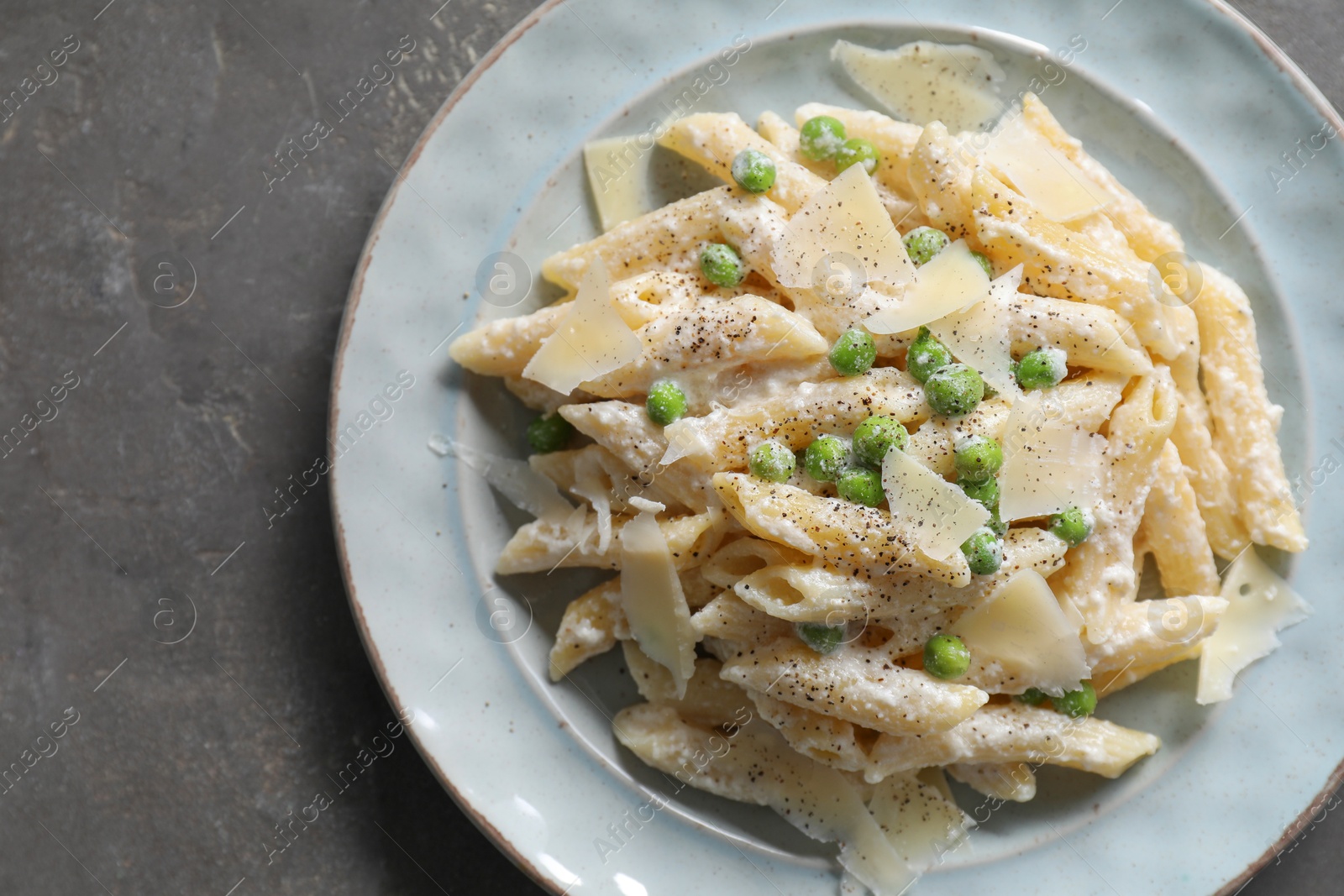 Photo of Delicious pasta with green peas, cheese and creamy sauce on grey table, top view