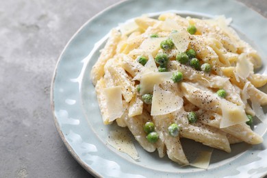 Photo of Delicious pasta with green peas, cheese and creamy sauce on grey table, closeup