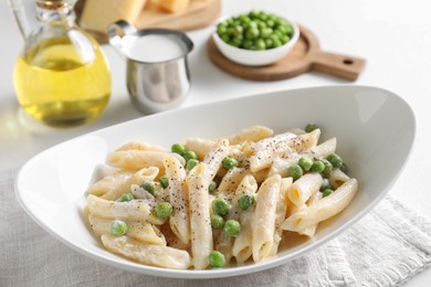 Delicious pasta with green peas and other ingredients on white table