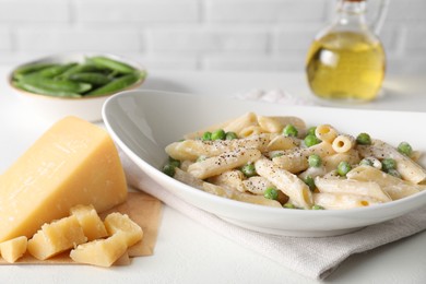 Delicious pasta with green peas, cheese and creamy sauce on white table