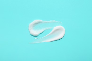 Photo of Samples of face cream on light blue background, top view