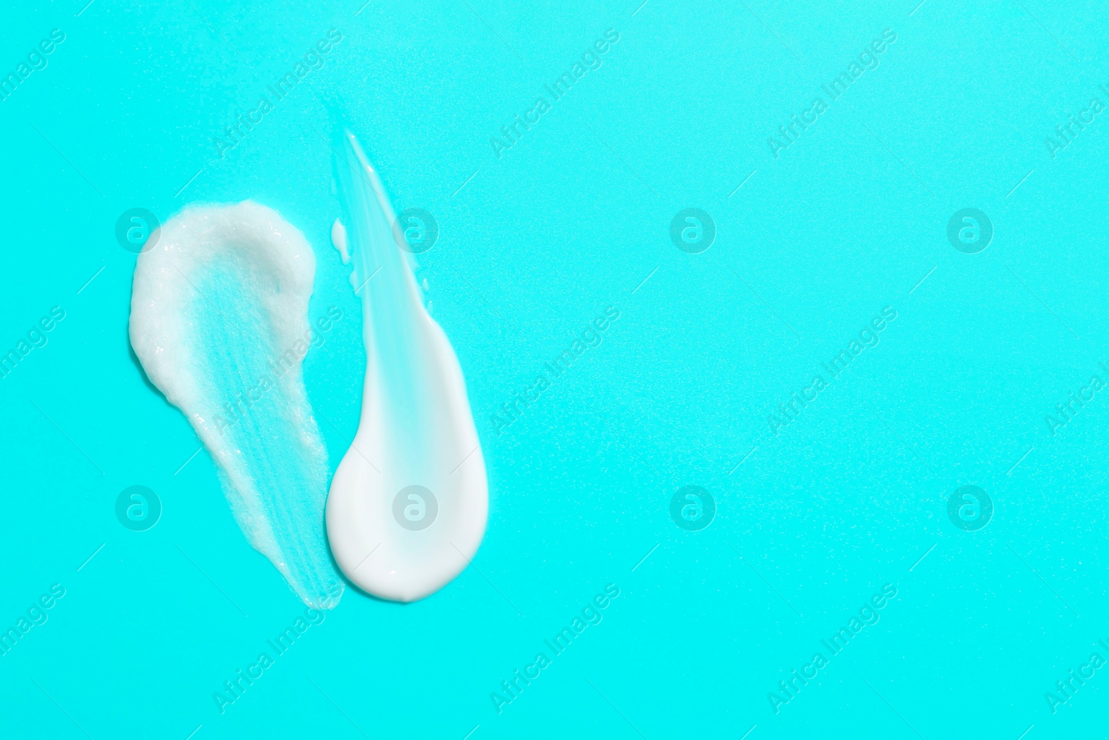 Photo of Samples of face cream on light blue background, top view. Space for text