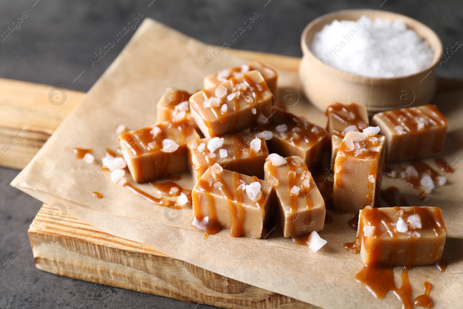 Photo of Tasty candies, caramel sauce and salt on grey table, closeup