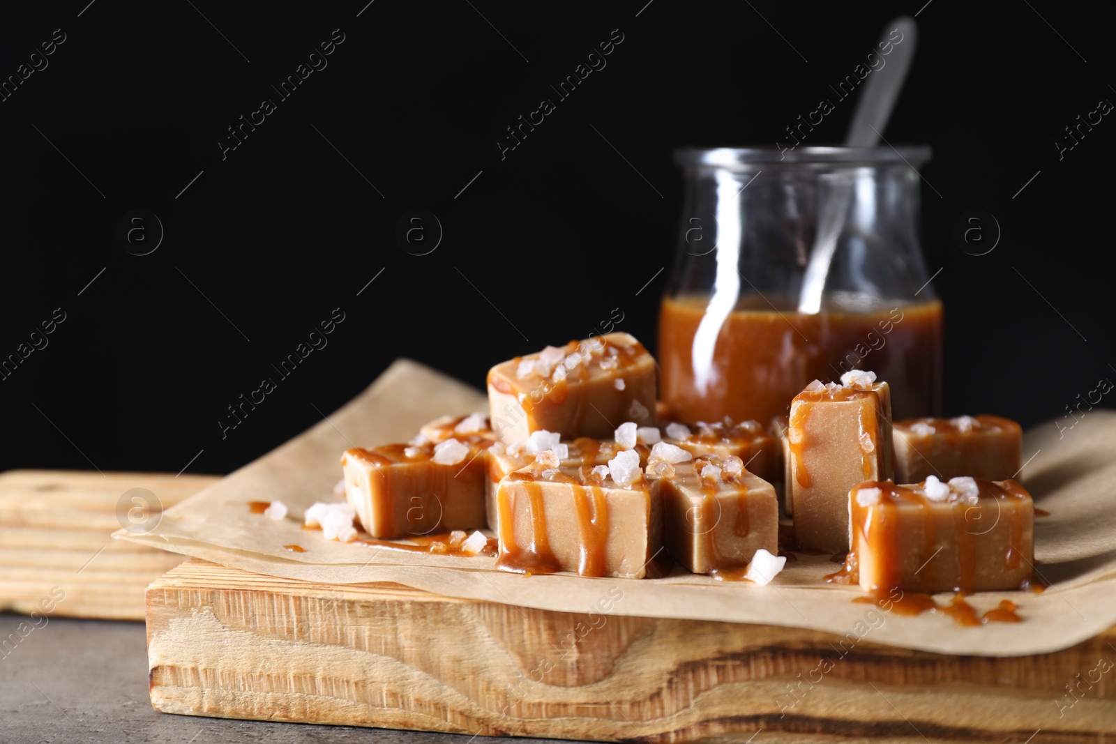 Photo of Tasty candies, caramel sauce and salt on grey table, closeup