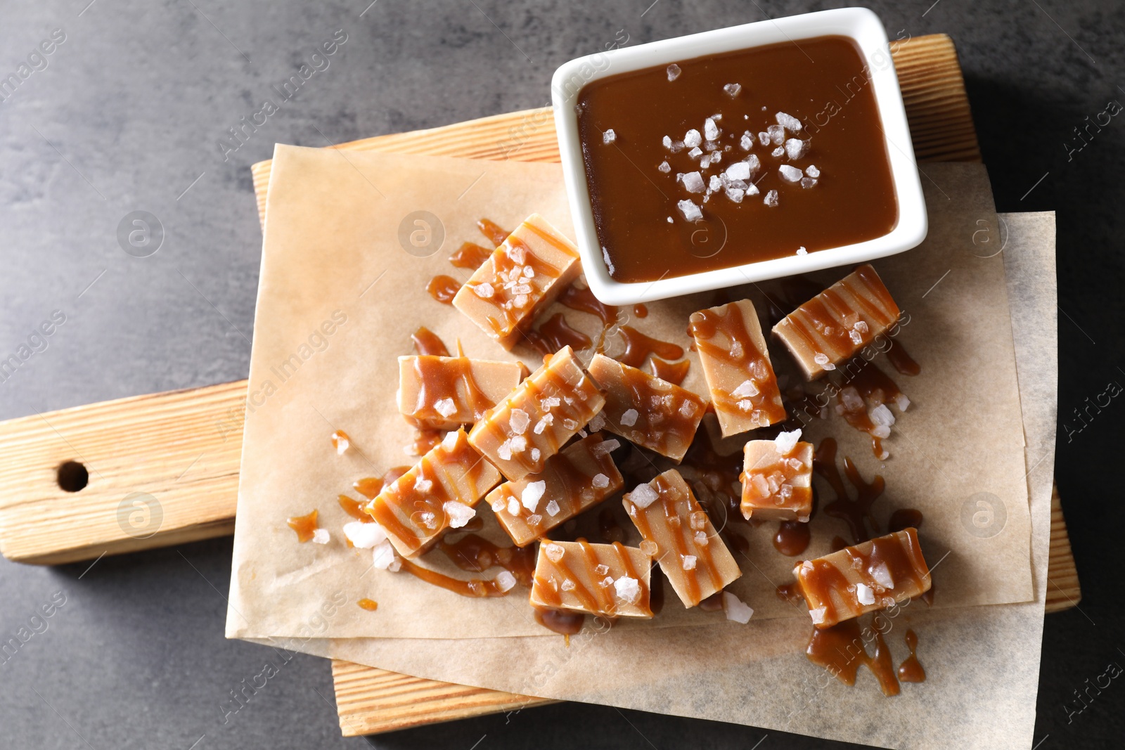 Photo of Tasty candies, caramel sauce and salt on grey table, top view