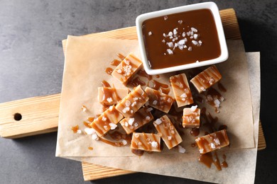 Photo of Tasty candies, caramel sauce and salt on grey table, top view