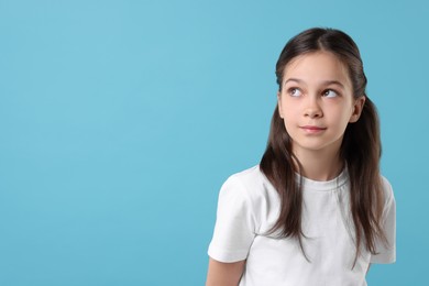 Portrait of beautiful girl on light blue background, space for text