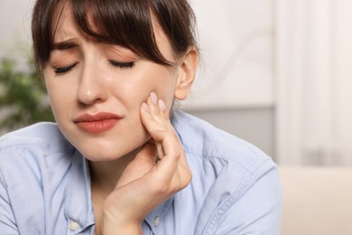 Photo of Upset young woman suffering from toothache indoors