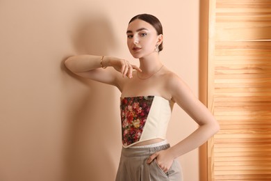 Photo of Beautiful young woman in stylish corset near beige wall