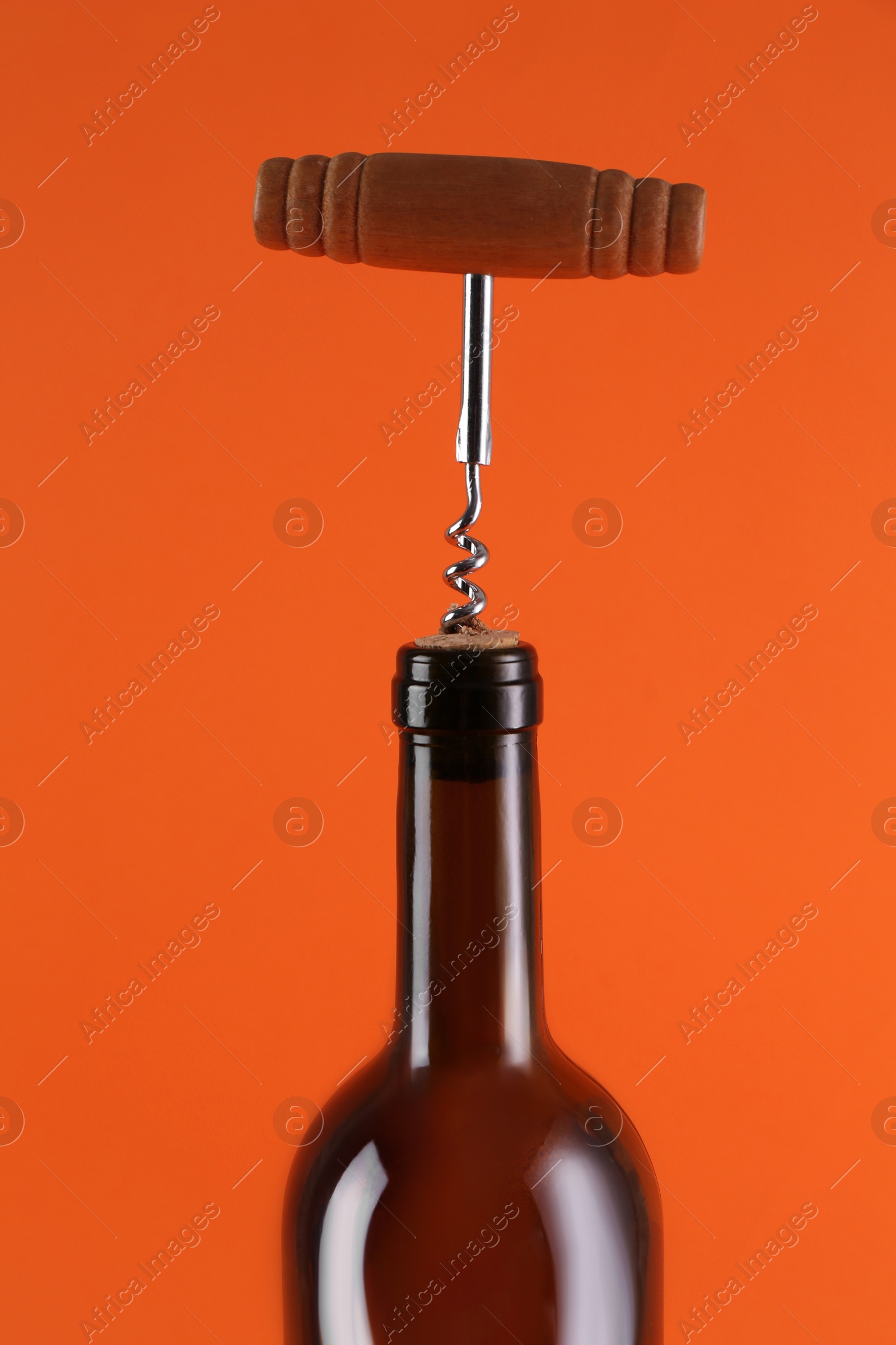 Photo of Wine bottle with corkscrew on orange background