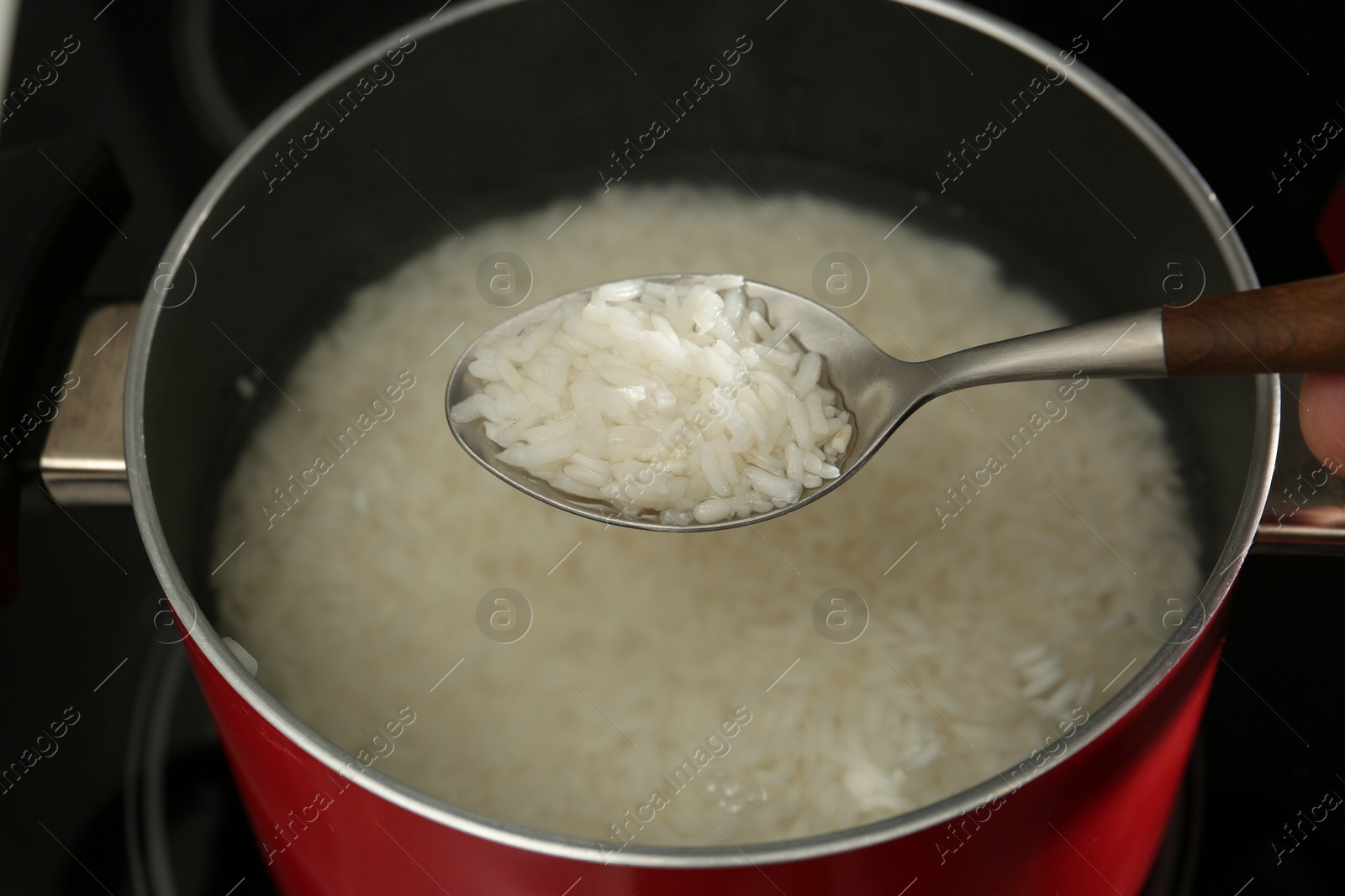 Photo of Taking boiled rice from pot with spoon, closeup