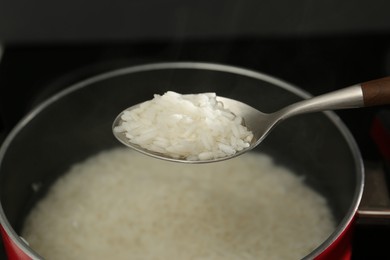 Photo of Taking boiled rice from pot with spoon, closeup