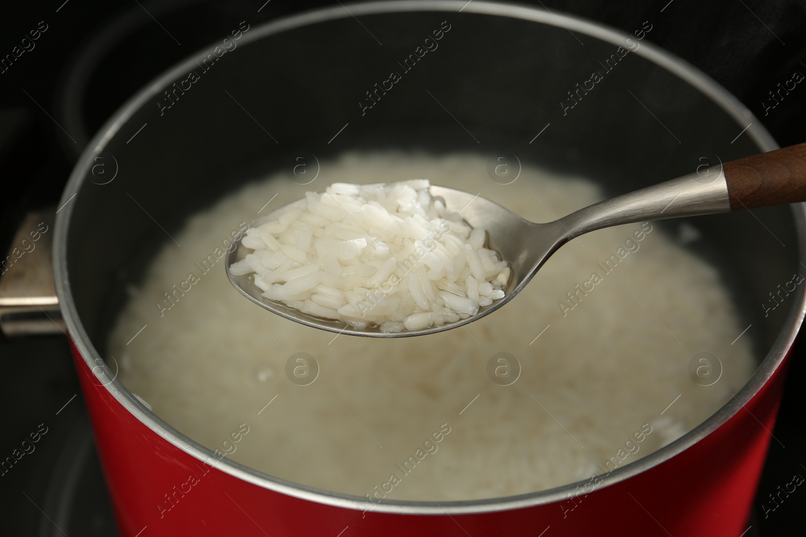 Photo of Taking boiled rice from pot with spoon, closeup