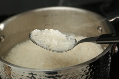 Photo of Taking boiled rice from pot with spoon, closeup