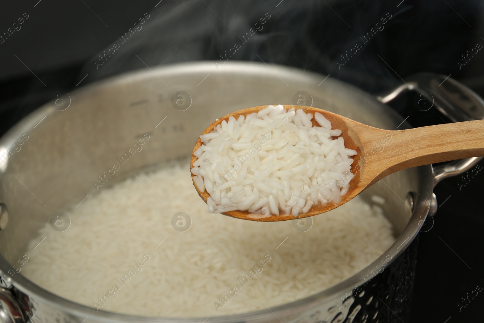 Photo of Taking boiled rice from pot with spoon, closeup