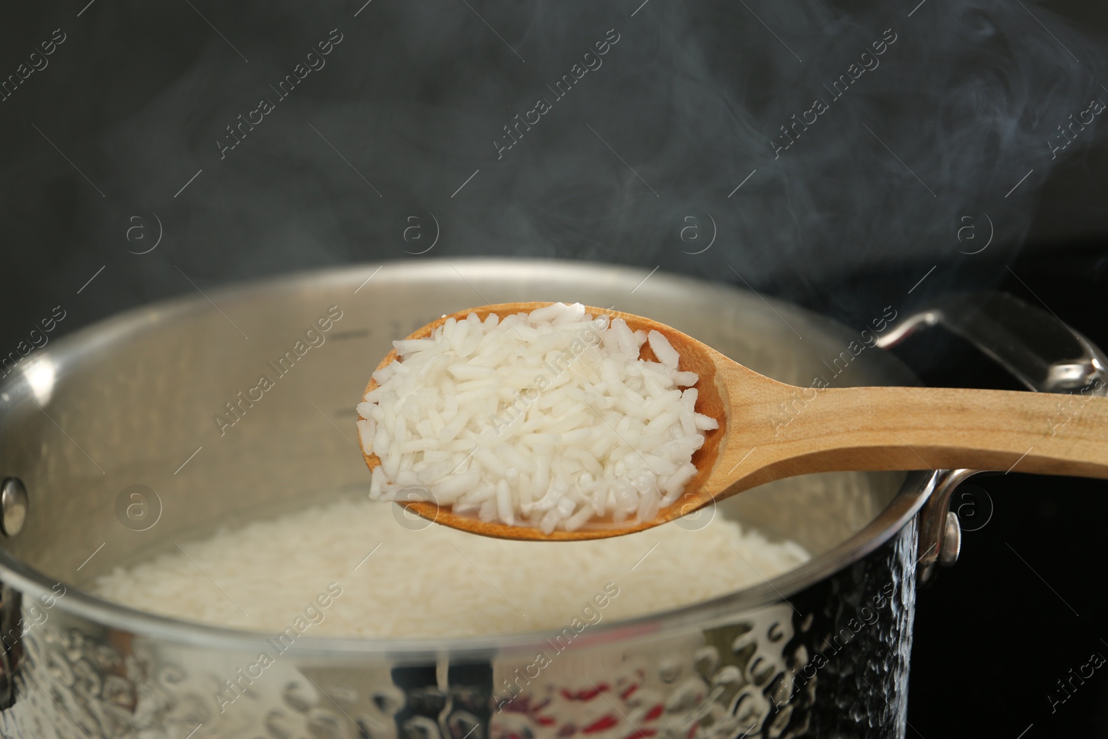 Photo of Taking boiled rice from pot with spoon, closeup