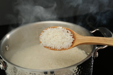 Photo of Taking boiled rice from pot with spoon, closeup