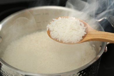 Photo of Taking boiled rice from pot with spoon, closeup